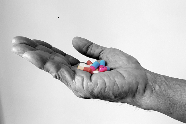 An outstetched hand holds several prescription pills